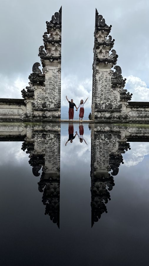 Pete and Danielle holding hands with arms raised between the Gates of Heaven in Bali