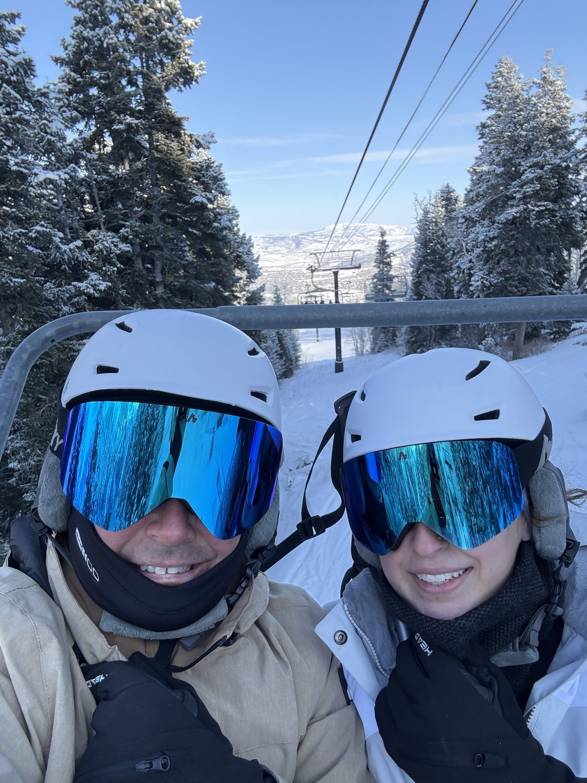Pete and Danielle in helmets and goggles on a ski lift